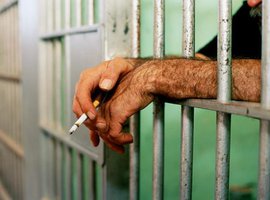 Руки заключённого через решетку